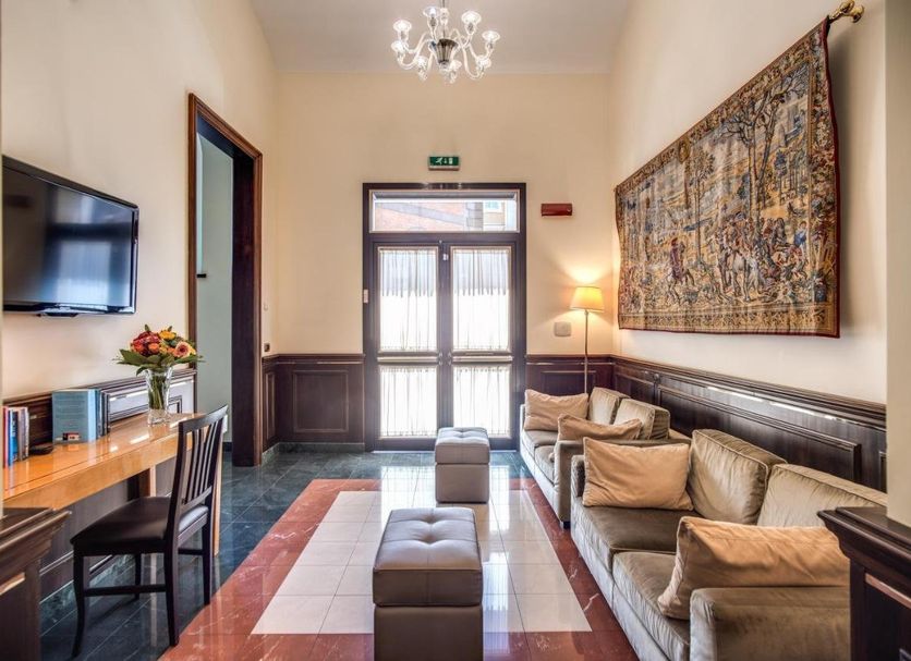 Hotel Diocleziano Rome lobby seating area with sofa, desk, wall art, and chandelier