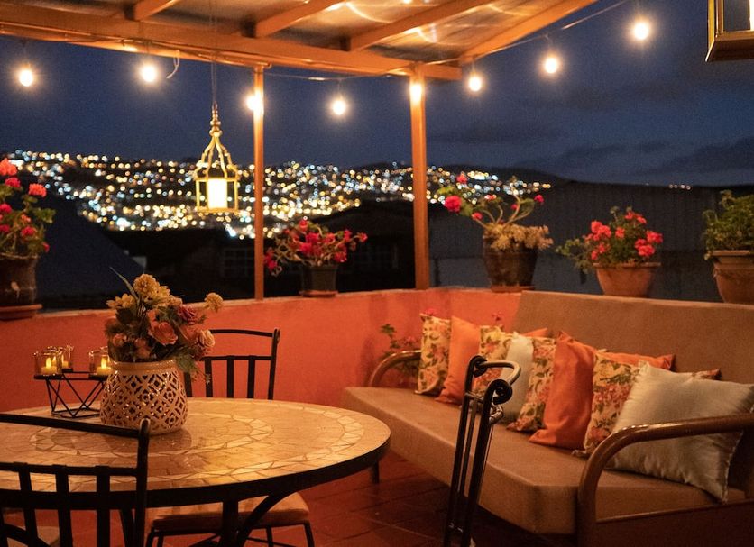 Rincón Familiar Hostel Boutique in Quito rooftop terrace with string lights, seating, and city night view