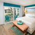 Margaritaville Island Reserve Riviera Cancun bedroom with king bed, patio doors, and garden-view lounge chairs in Puerto Morelos