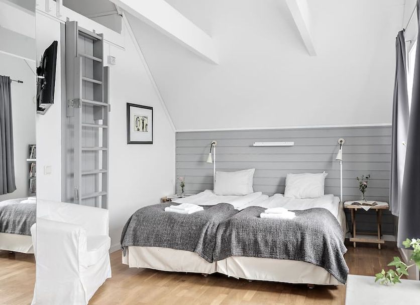 Bergabo, Rönnäng: twin beds in a bright attic room with sloped ceiling and gray curtains