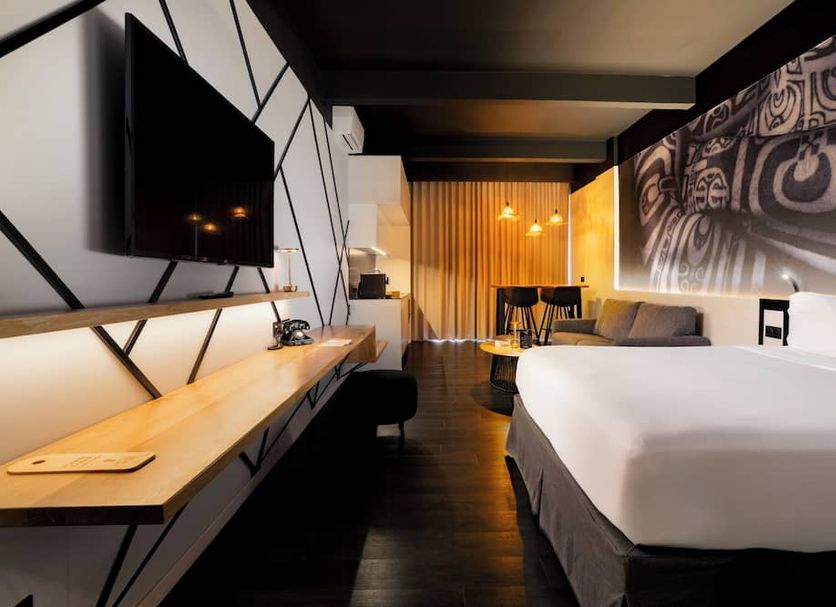 Boutique Hôtel Kon Tiki Tahiti room in Papeete with bed, desk, sofa and geometric wall design