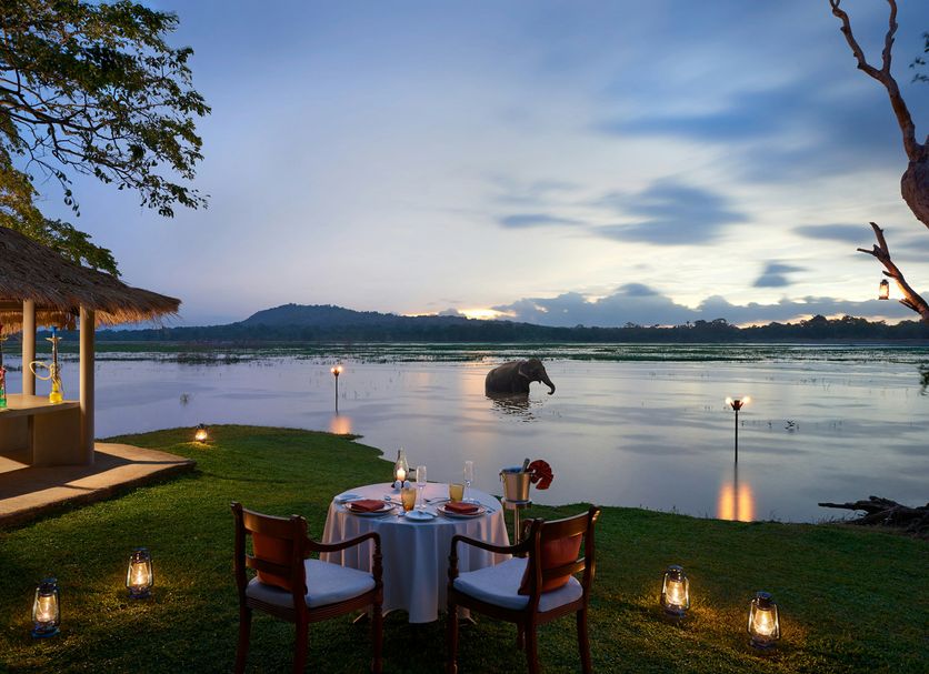 Habarana Village by Cinnamon in Habarana: lakeside dining setup at sunset with water and hills