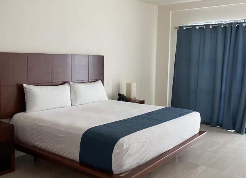 Marena Suites and Apartments in Mazatlán: a king bed with blue runner, nightstands and blue curtains