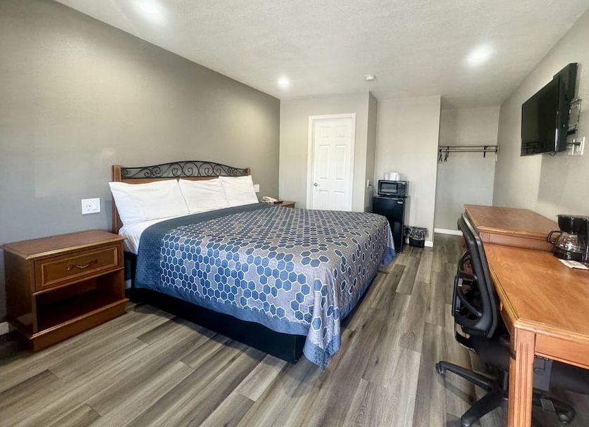 Villa Court Inn Oroville guest room with queen bed, desk, TV, and wood-look flooring in Oroville