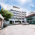 The Singora Hotel, Songkhla: exterior view with entrance drive, parked cars, and flagpoles