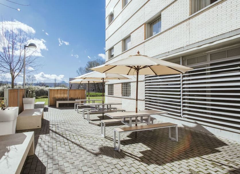 Residencia Universitaria Resa Los Abedules in Pamplona, outdoor terrace with picnic tables and umbrellas