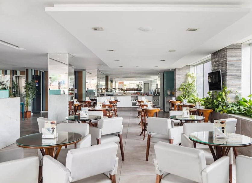 Citi Hotel Express Caruaru lounge with white chairs, glass tables, and large windows in Caruaru
