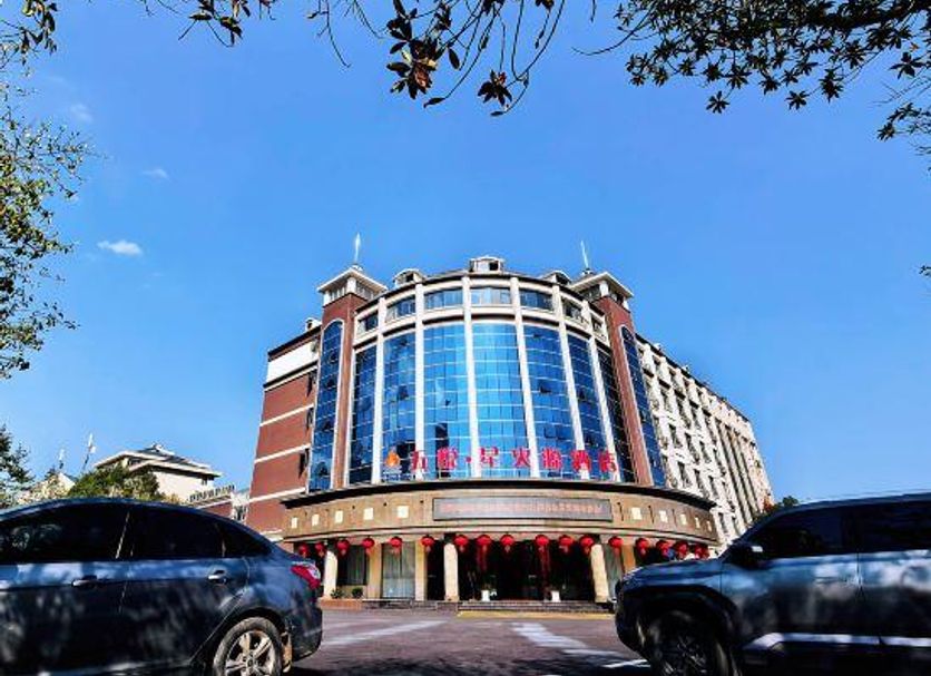 Wuyue Yuexin Hotel (Jinggangshan) in Ji'an, curved glass-front hotel exterior under blue sky