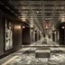 Bottleworks Hotel Indianapolis hallway with framed black-and-white portraits and patterned ceiling