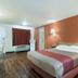 Motel 6 Newport News, VA guest room with king bed, wood-look floor, desk, and orange accent wall