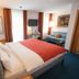 Zollamt Design Hotel Kaiserslautern guest room with bed, sofa, TV and colorful curtains