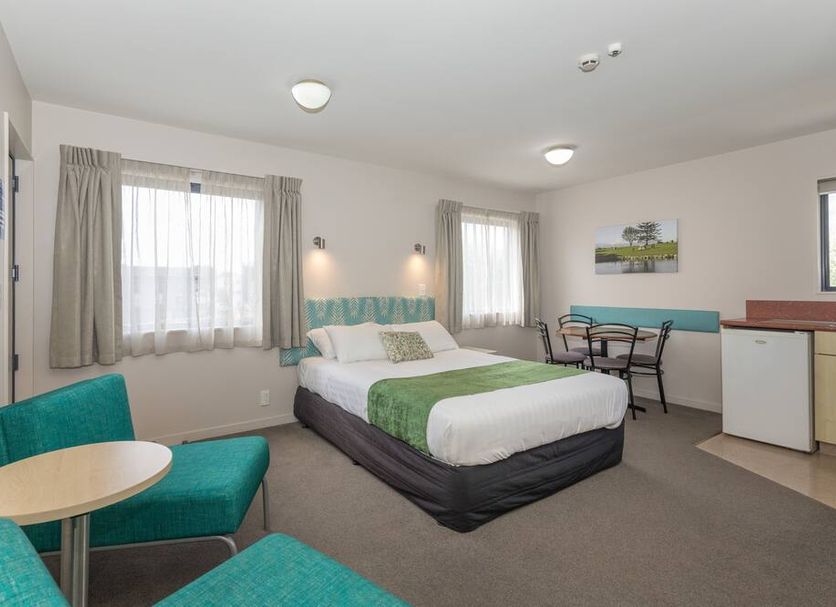 Bella Vista Motel New Plymouth room with bed, teal seating, desk, and kitchenette