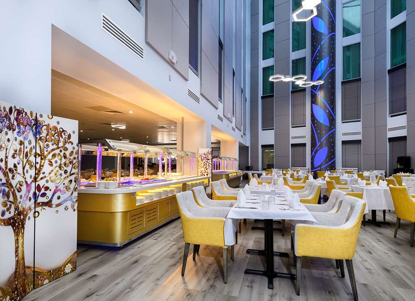 Atrium Hotel Heathrow in Hounslow dining area with yellow chairs and buffet tables