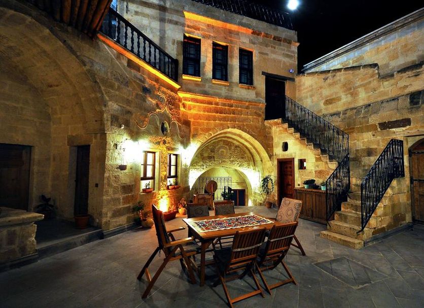 Has Cave Konak in Ürgüp courtyard dining area with stone walls, stairs, and warm lighting at night