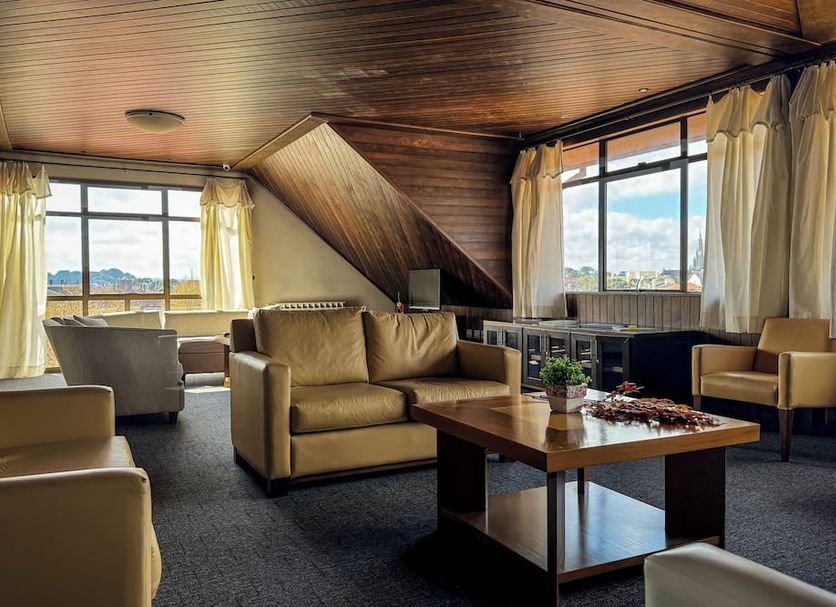 Hotel Tissiani Canela lounge with tan seating, wood ceiling, and mountain-view windows in Canela