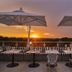 Sunset rooftop terrace at Hotel Villa Pamphili Roma in Rome with striped seating and umbrellas
