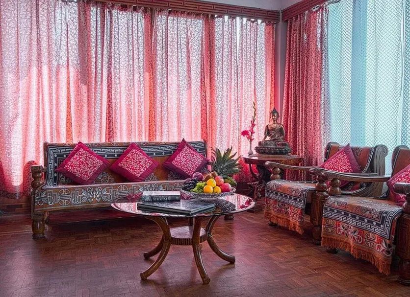 Hotel Tashi Delek in Gangtok lounge with carved wooden sofas, pink cushions and a central coffee table