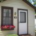 The Beach House in Mackinaw City, small cottage exterior with front door, window box flowers, and number 10