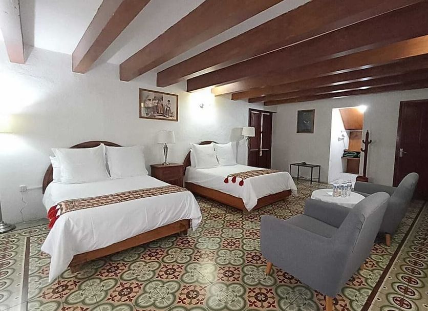 Posada del Virrey in Tequisquiapan: spacious hotel room with two beds, armchair, wood-beam ceiling