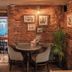 Dog and Partridge by Greene King Inns in Bury St. Edmunds, brick-walled dining area with round table and chairs
