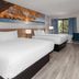 Days Inn by Wyndham Mason City guest room with two beds, window, TV, and blue chairs