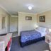 Cootamundra Gardens Motel room in Cootamundra with a bed, bedside table and small dining area