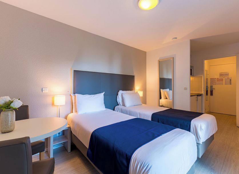 Séjours & Affaires Pantin Charles De Gaulle guest room with two twin beds and desk in Pantin