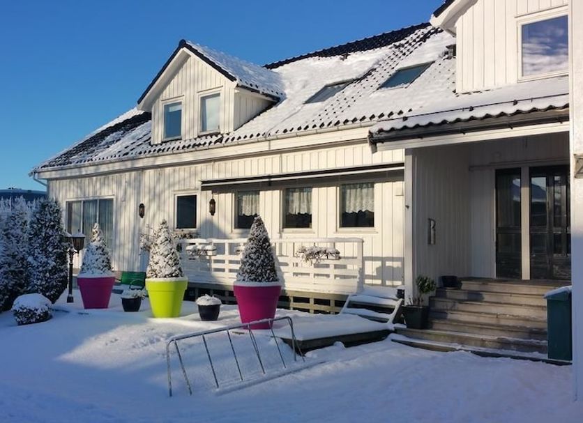 Skeisvang Gjestgiveri in Haugesund, snow-covered hotel exterior with colorful potted plants and sun loungers