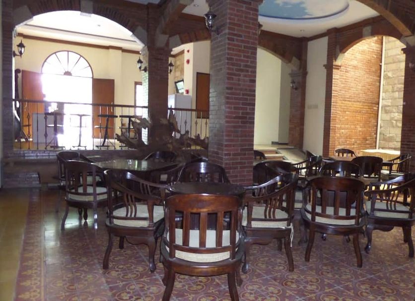 Jacatra Homestay in Malang lounge with wooden chairs, brick arches, and a patterned tile floor