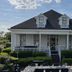 1842 Inn in Macon with a white porch, manicured shrubs, and outdoor dining tables in front