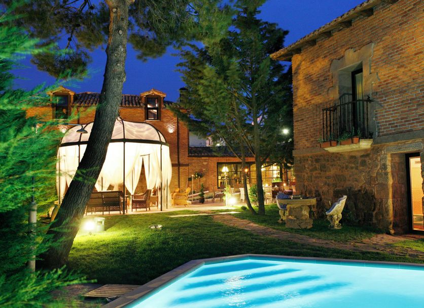 Hotel Boutique Real Casona de las Amas in Azofra: lit outdoor pool and garden courtyard at night