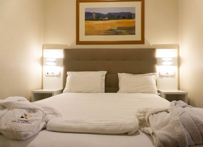 Residencial Lar do Areeiro in Lisbon, a neatly made double bed with bedside lamps and wall art