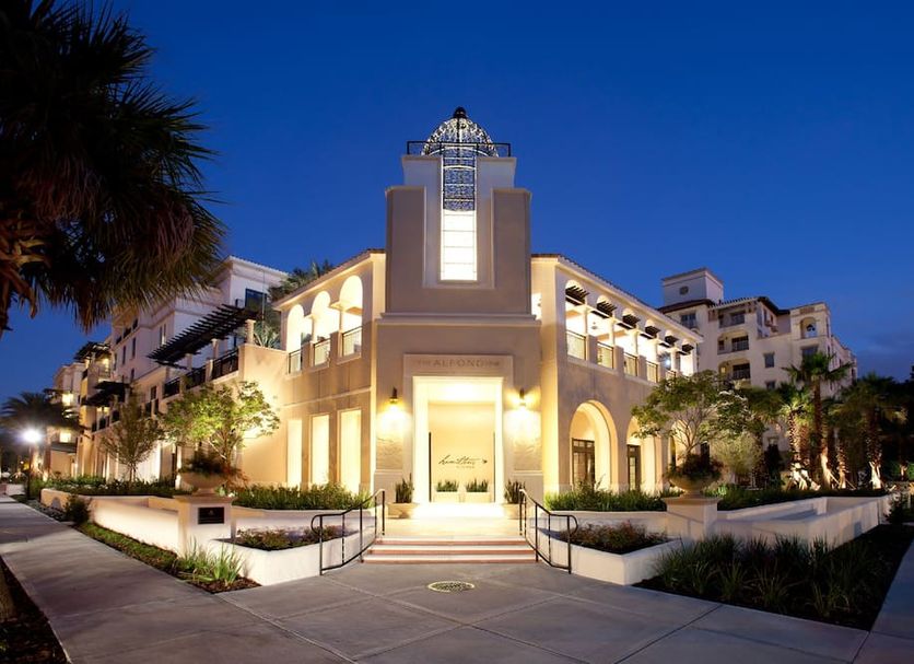 The Alfond Inn in Winter Park at dusk, with illuminated entryway and palm-lined courtyard