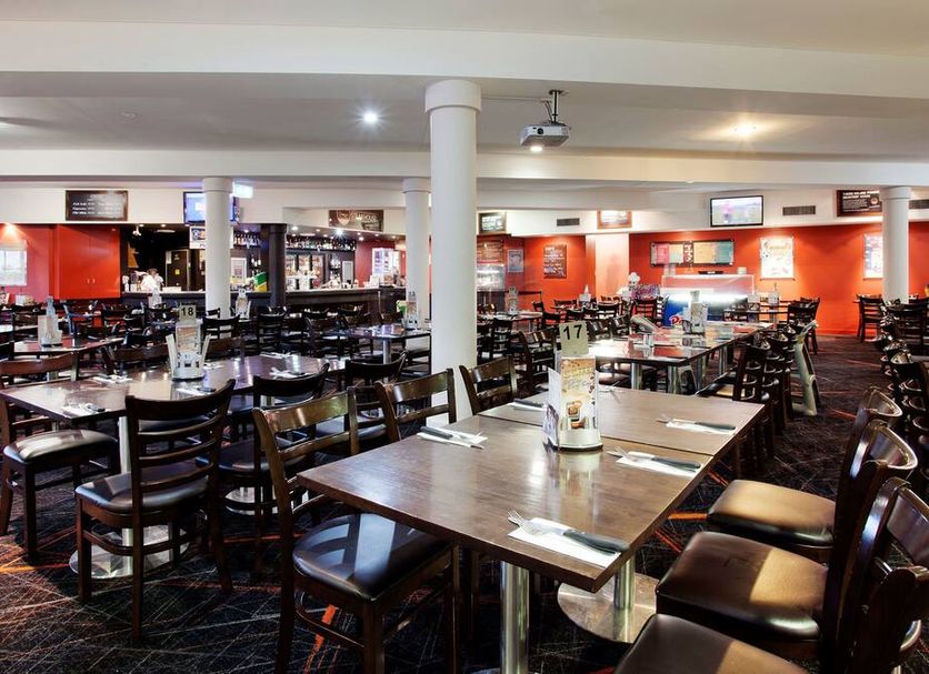 Vale Hotel Townsville dining room with tables, chairs, and orange walls