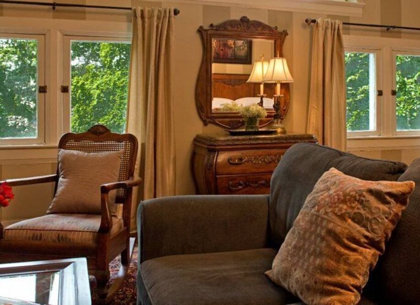Beaufort House Inn Asheville guest room with upholstered sofa, armchair, windows and wooden dresser