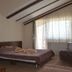 Magic Club Bușteni guest room with bed, sofa, TV, and sheer curtains by a bright window