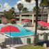Bposhtels Orlando Disney in Kissimmee with outdoor pool, red umbrellas, palm trees and lounge chairs