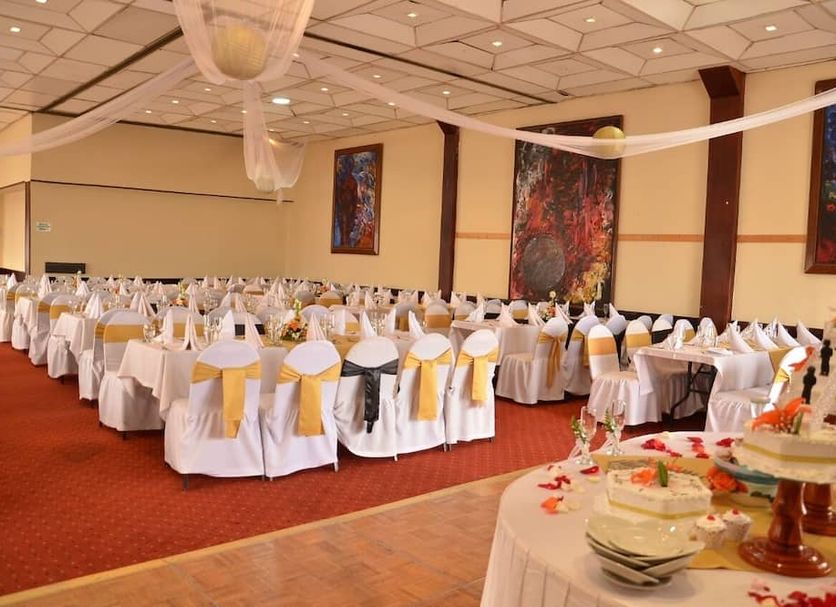 Hotel Zuhe, Paipa banquet hall set with round tables, white chair covers and yellow sashes