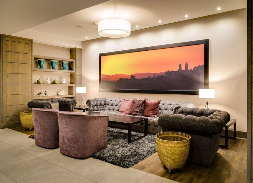 Anew Hotel Hatfield Pretoria lounge with sofa, armchairs and framed sunset city art in Pretoria
