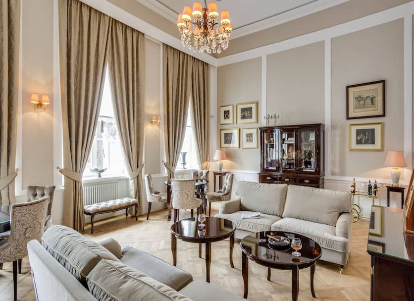 Hotel Bellotto Warsaw elegant suite with chandelier, tall windows, sofa seating and classic decor