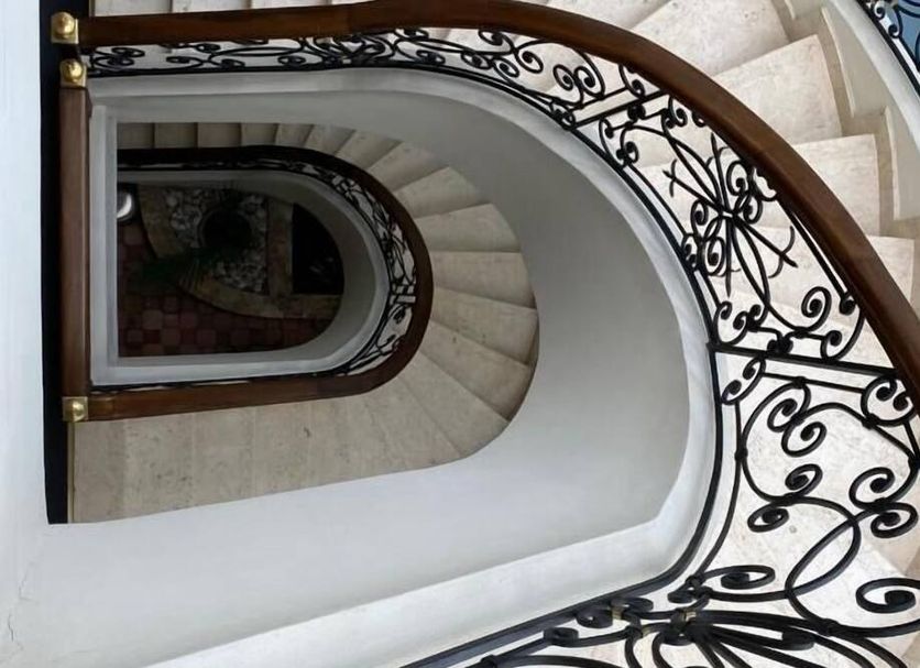 Hotel Castilla Real in Pereira: ornate spiral staircase with white steps and wrought-iron railing