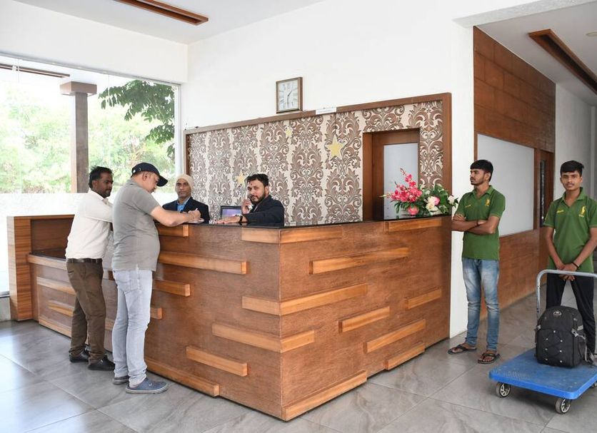 Pushpak Resort Shirdi lobby reception desk with staff and guests near luggage cart