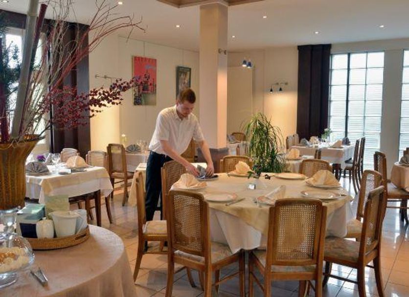 Logis Auberge des Vieux Chênes in La Chapelle-aux-Brocs dining room with set tables and a server