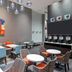 Hampton Inn & Suites Atlanta Buckhead Place breakfast area with tables, chairs, coffee station and wall art