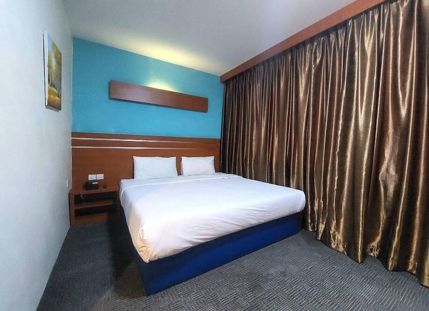 D'merlion Hotel Batam guest room with double bed and floor-to-ceiling curtains