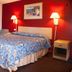 Scottish Inn Downtown Jacksonville room with double bed, red accent wall, bedside lamps, and armchair in Jacksonville