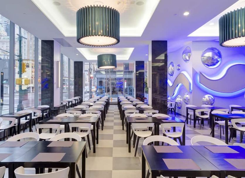Hotel Riu Plaza New York Times Square dining room with rows of tables and modern blue lighting in New York