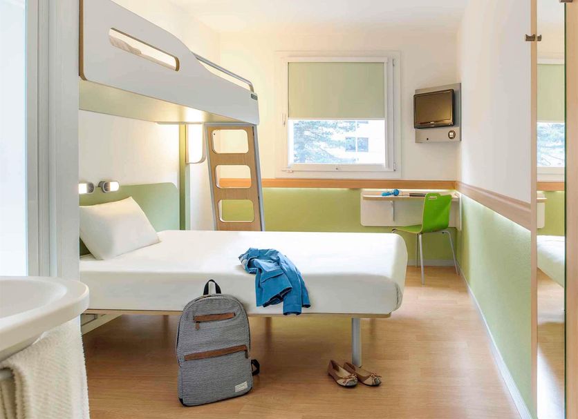Ibis Budget Dijon Saint Apollinaire room with bunk bed, single bed, desk and window in Saint-Apollinaire