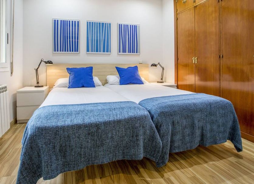 Mola Hostel Madrid twin bedroom with blue accents, bedside lamps and wooden wardrobes