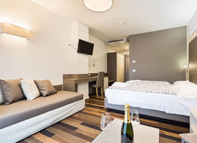 Hotel Gardesana room in Riva del Garda with bed, sofa, desk and TV